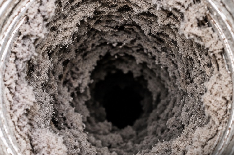 The inside of a dryer duct before cleaning, packed with thick grey lint